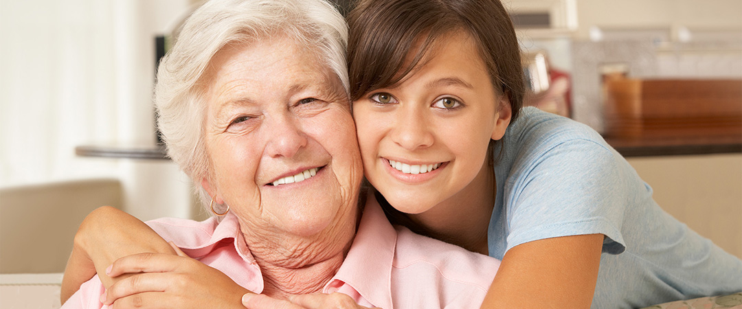 Young woman with her arms around an elderly woman's shoulders
