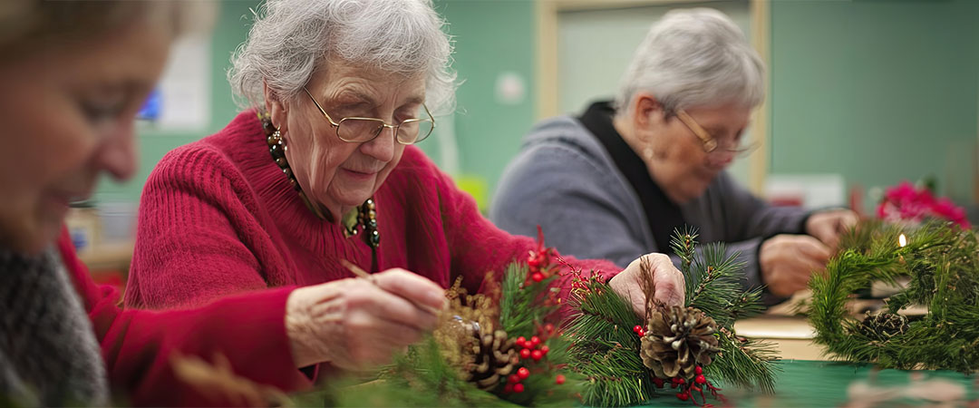 Three seniors sat at a table doing holiday activities together.